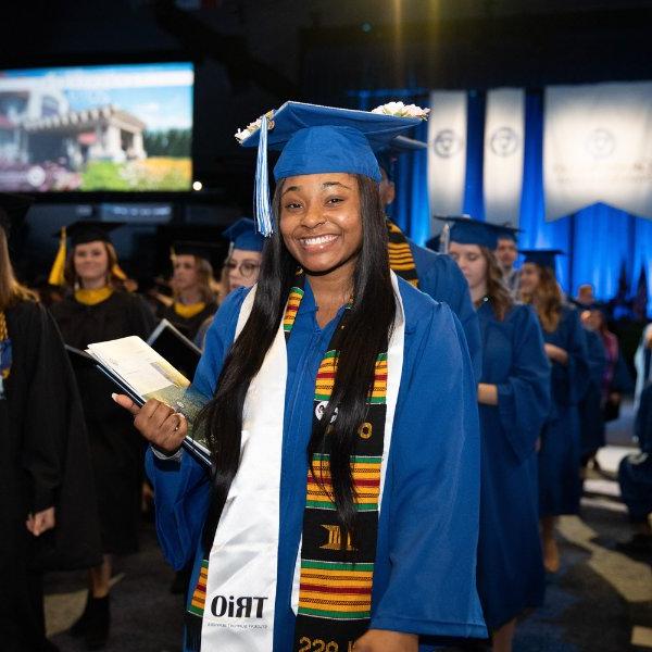 a 2019 graduate pictured at commencement with a TRIO stole, cap and gown